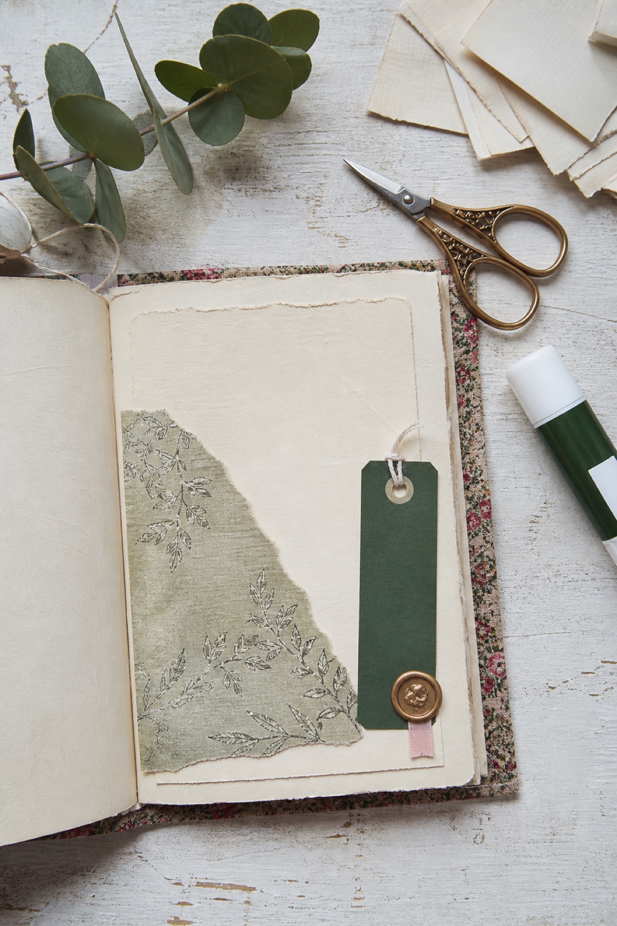 Realistic cream journal spread using sage paper, a forest green tag, a gold seal, and one small blush ribbon accent